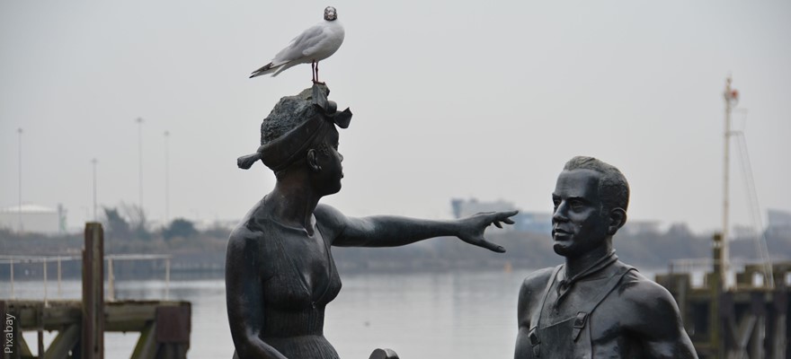 פסל שני אנשים כשאחד מורה דרך לשני בעוד ציפור אמיתית על ראש הפסל