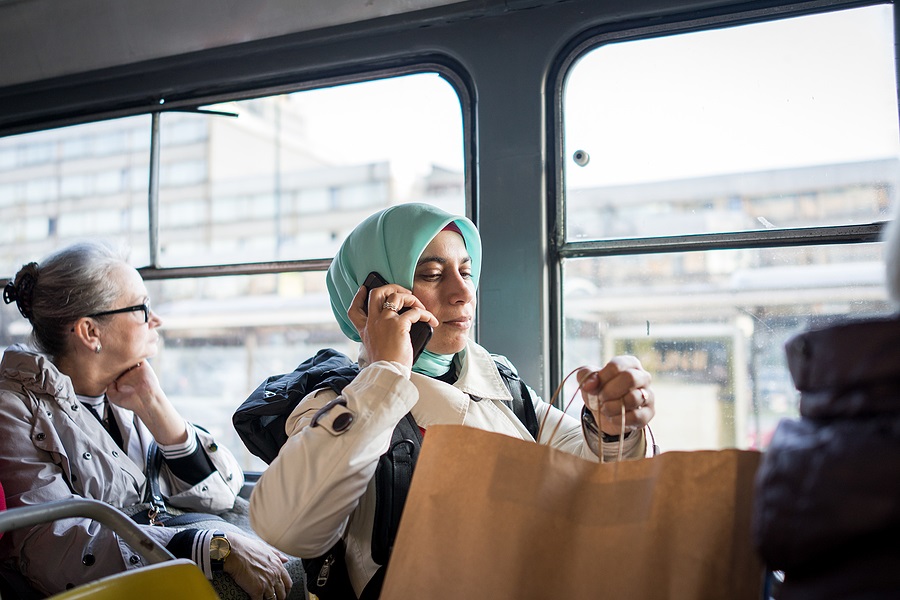 אישה עם חיג'אב משוחחת בטלפון באוטובוס